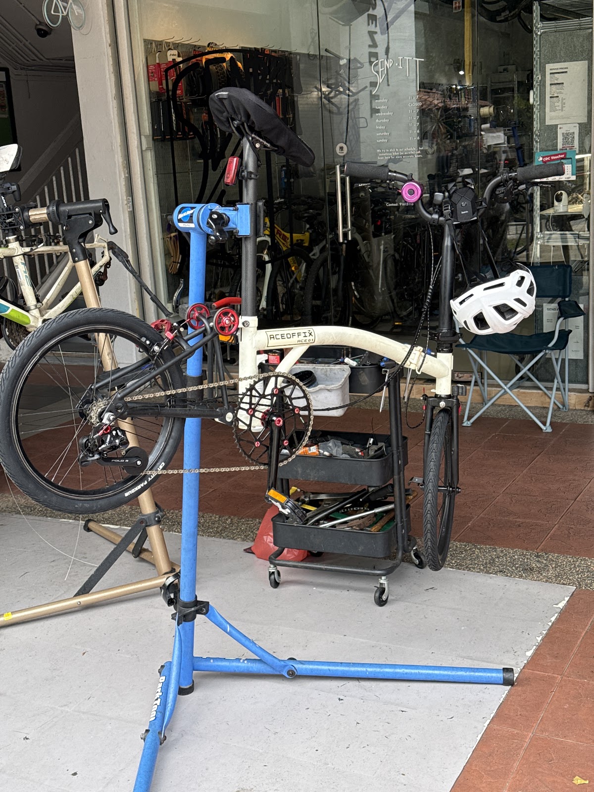 Folding bike on a Park Tool repair stand outside the Send Itt shop