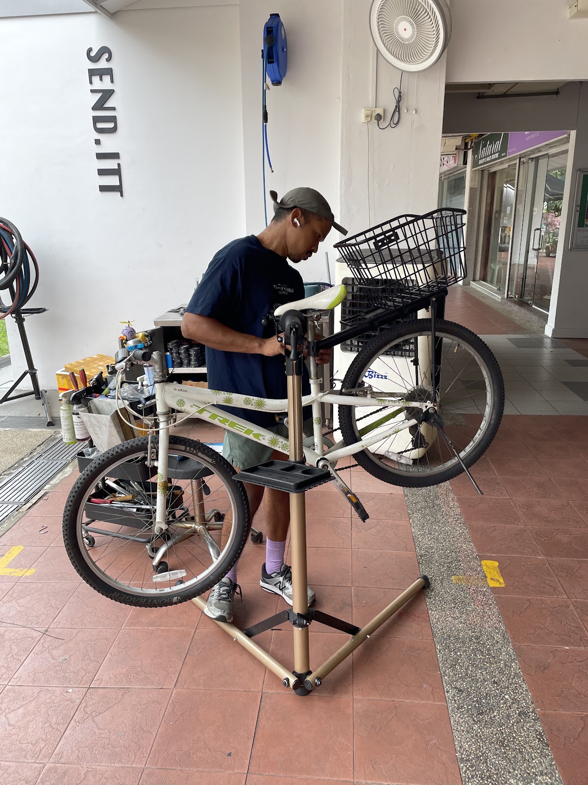 Mechanic working on a kids Trek bike under the SEND.ITT sign